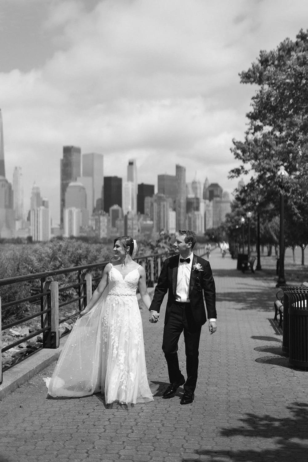 Black and white photo of the couple walking the path holding hands. 