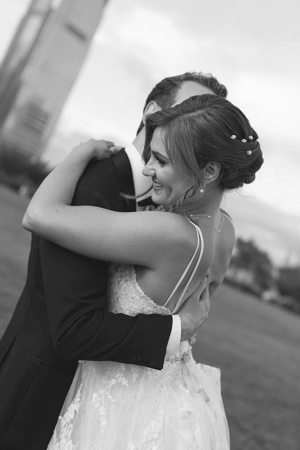 The bride holds her groom close as she smiles happily. 