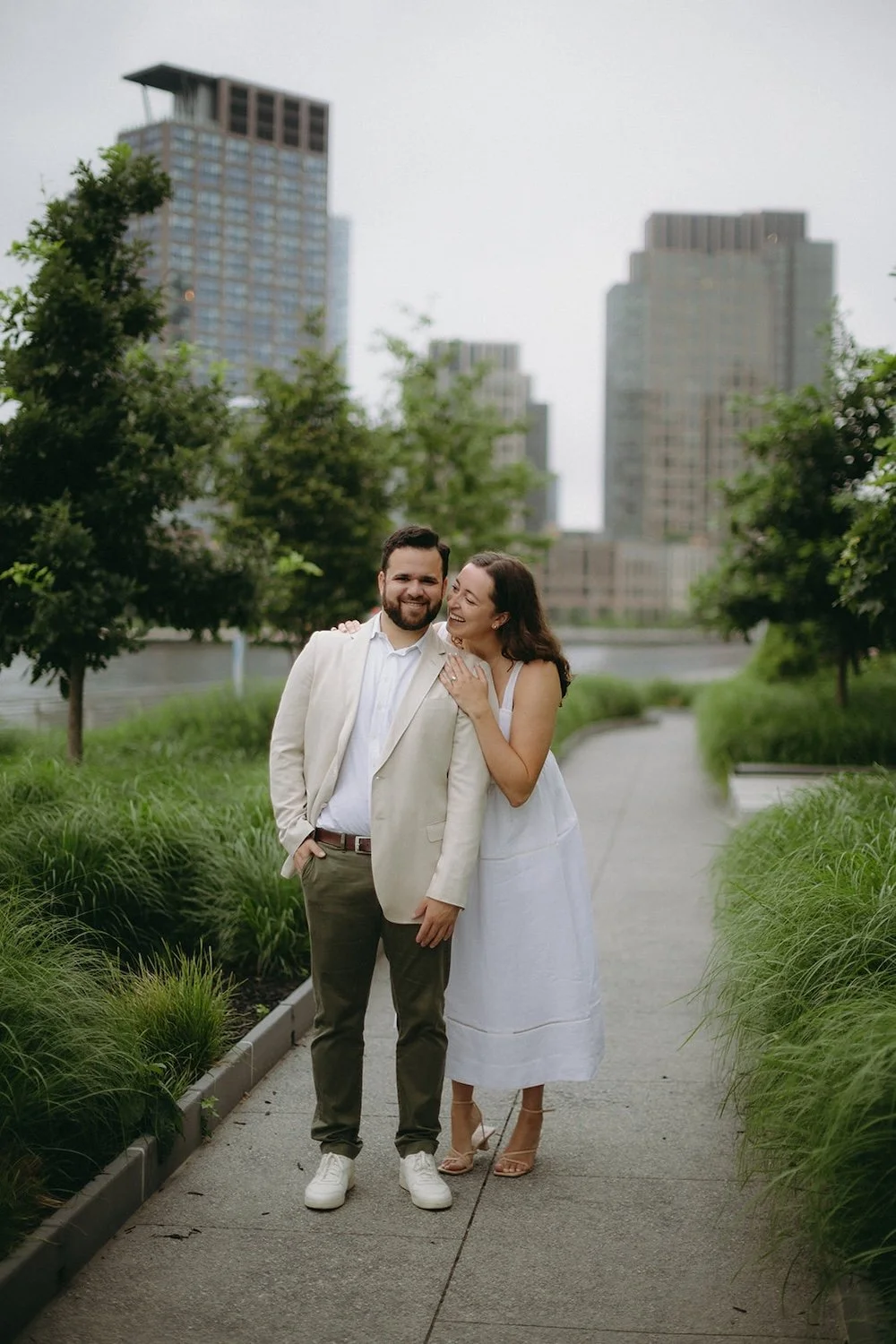 The future bride reaches over the grooms shoulder with a smile. 