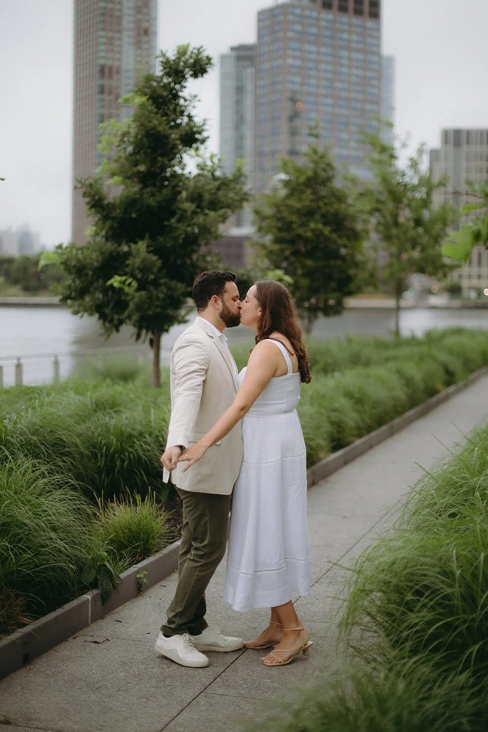 The couple fan their hands out while reaching in for a kiss. 