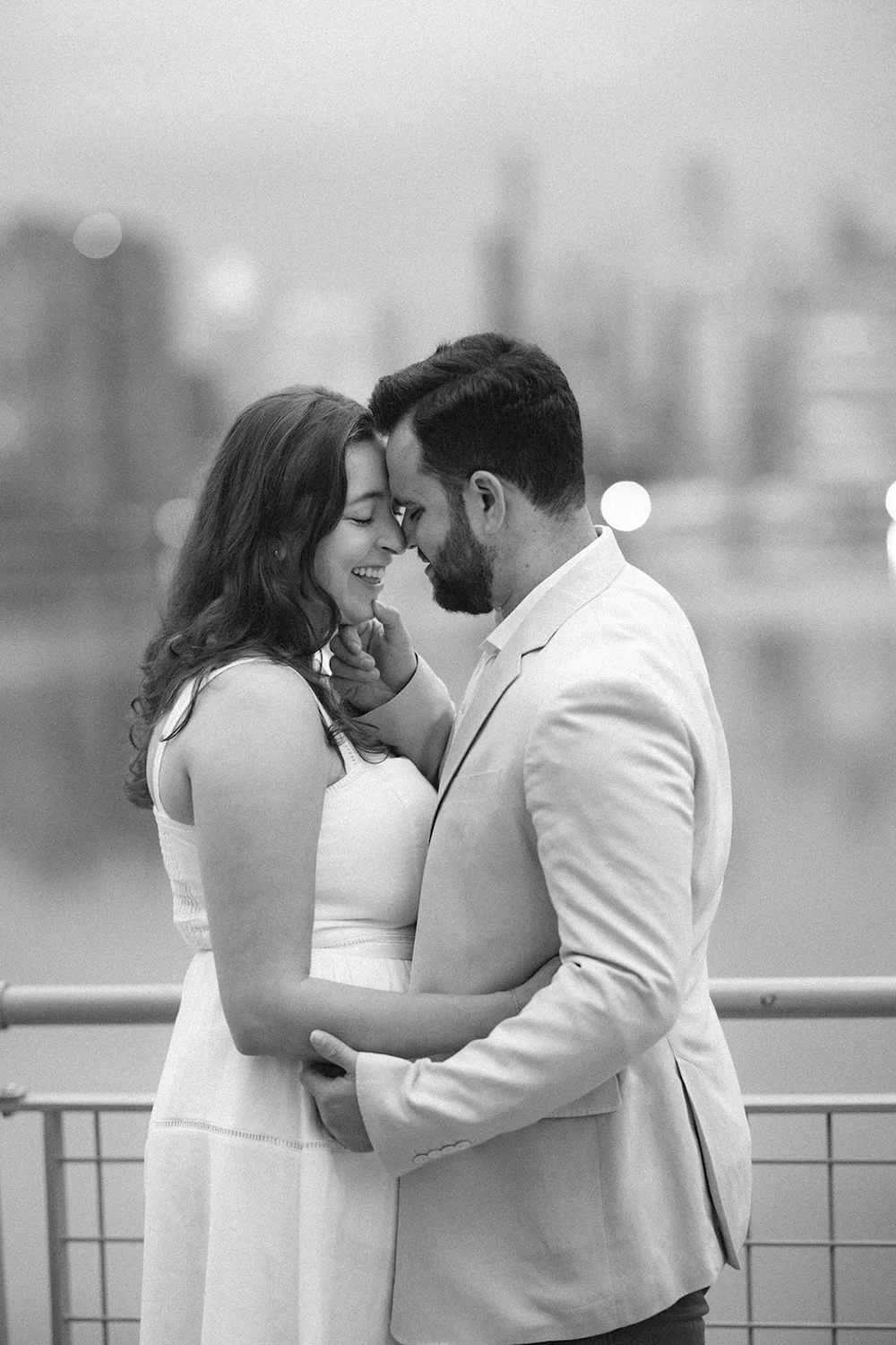 Black and white photo of the couple holding one another close leaning in for a kiss. 
