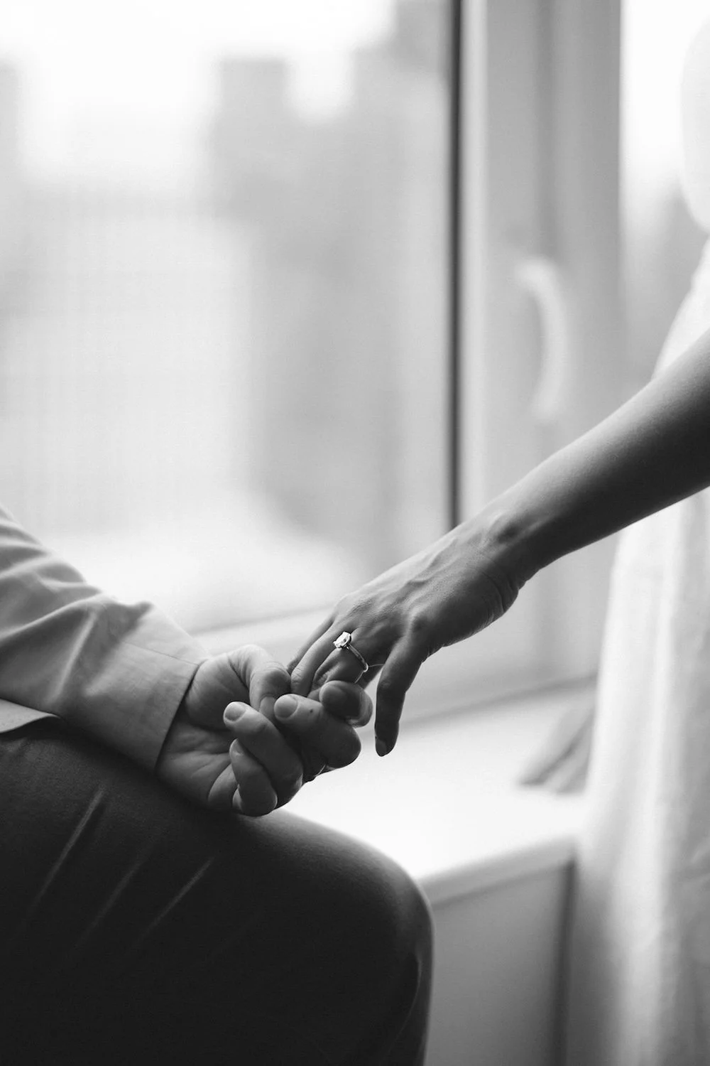 Black and white photo of the future groom holding his future brides hand. 