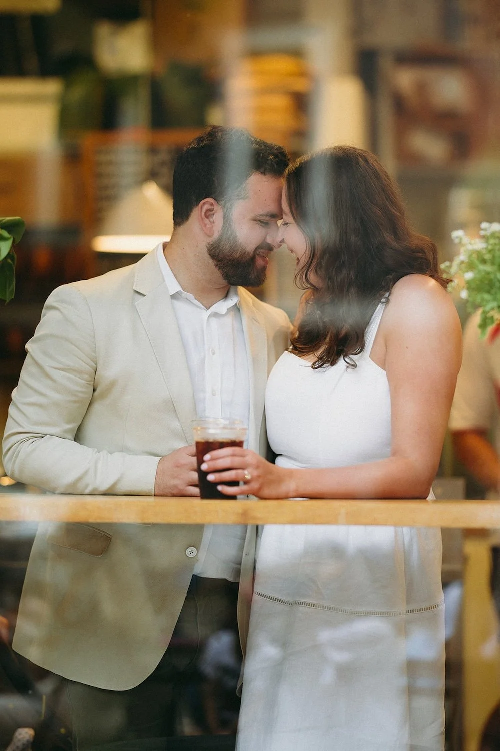 The couple stands in the window of their favorite coffee shop. 