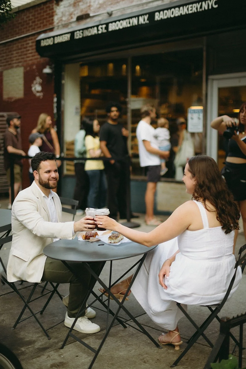 The couple sit outside their favorite coffee shop enjoying coffee and pastries. 