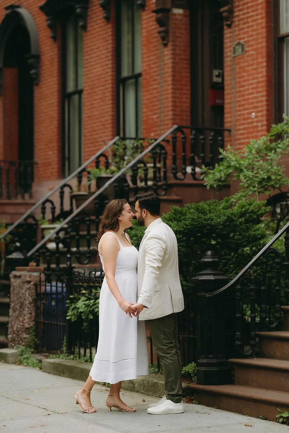 The couple hold hands as they stand close to sneak a kiss. 
