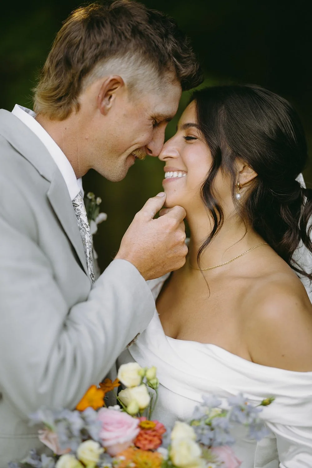 The groom holds the chin of his bride as he stares into her eyes. 