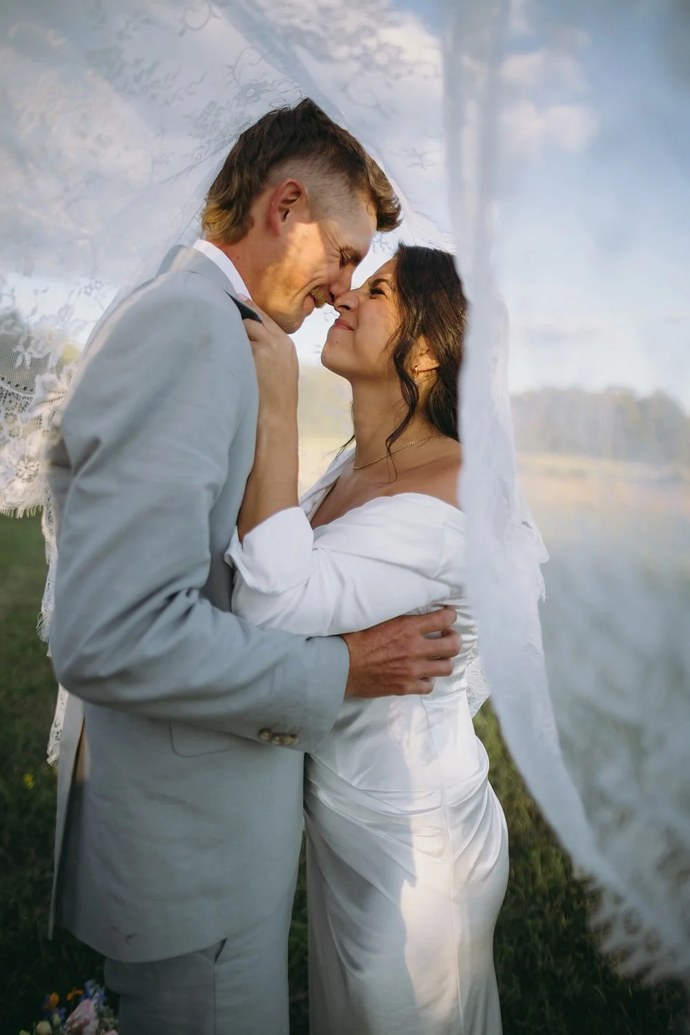 The bride and groom toe noses under the brides veil. 