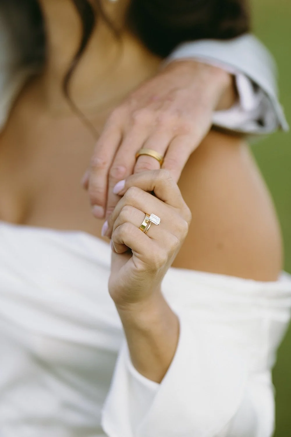 Detail photo of the bride holding her grooms hand with their wedding bands in place. 