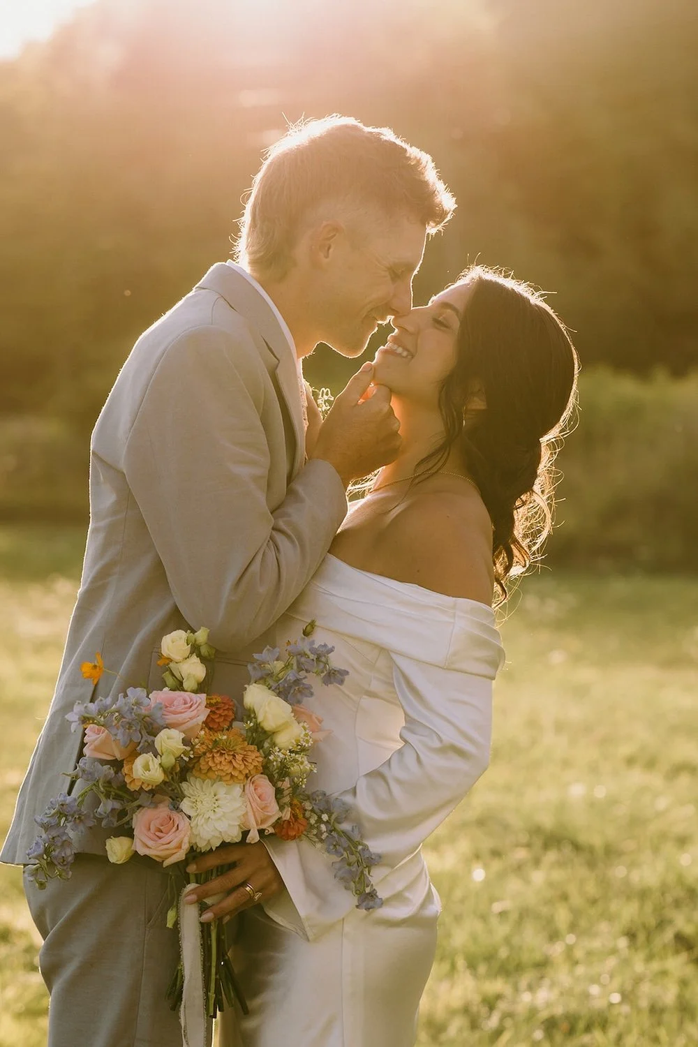 The groom holds his bride's face close as he reaches in to kiss her. 