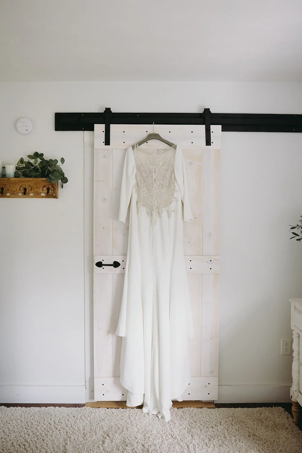 The wedding gown hangs off a sliding barn door. 