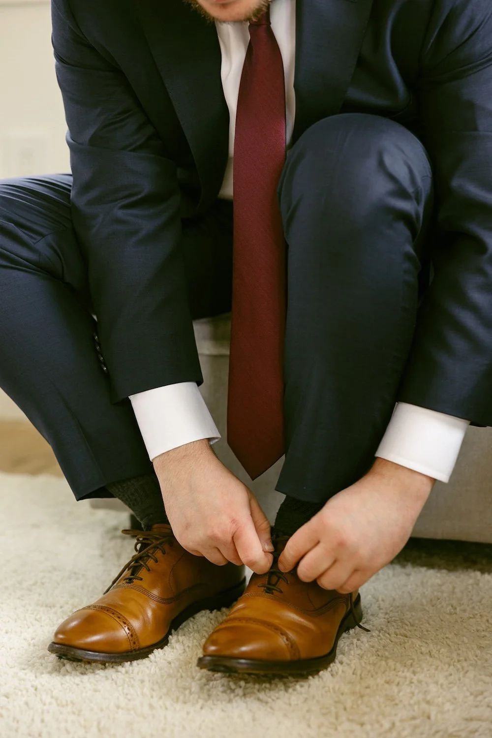 The groom ties the laces of his shoes. 
