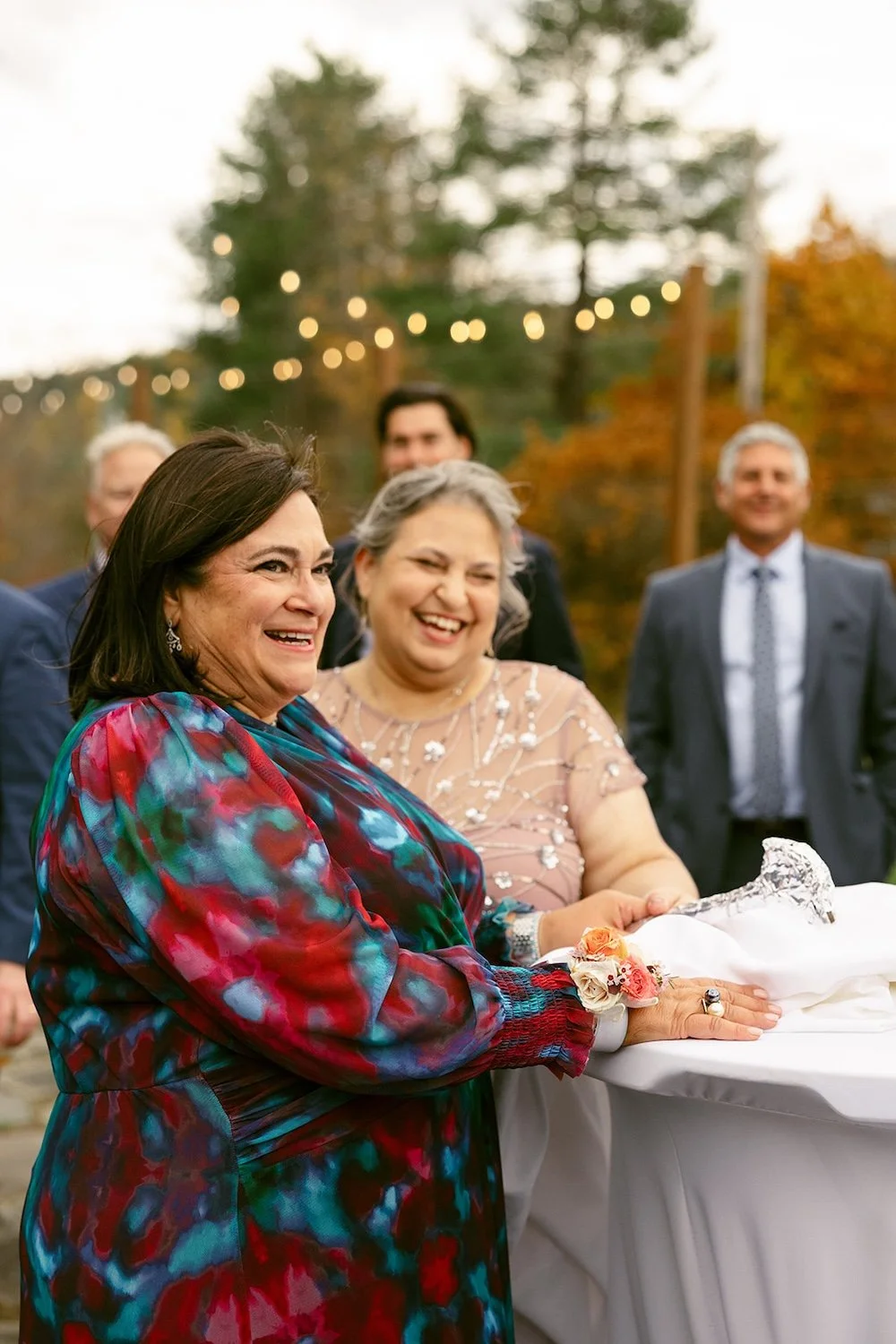 Mother of the bride and groom stand side by side with smiles in celebration of the happy couple. 