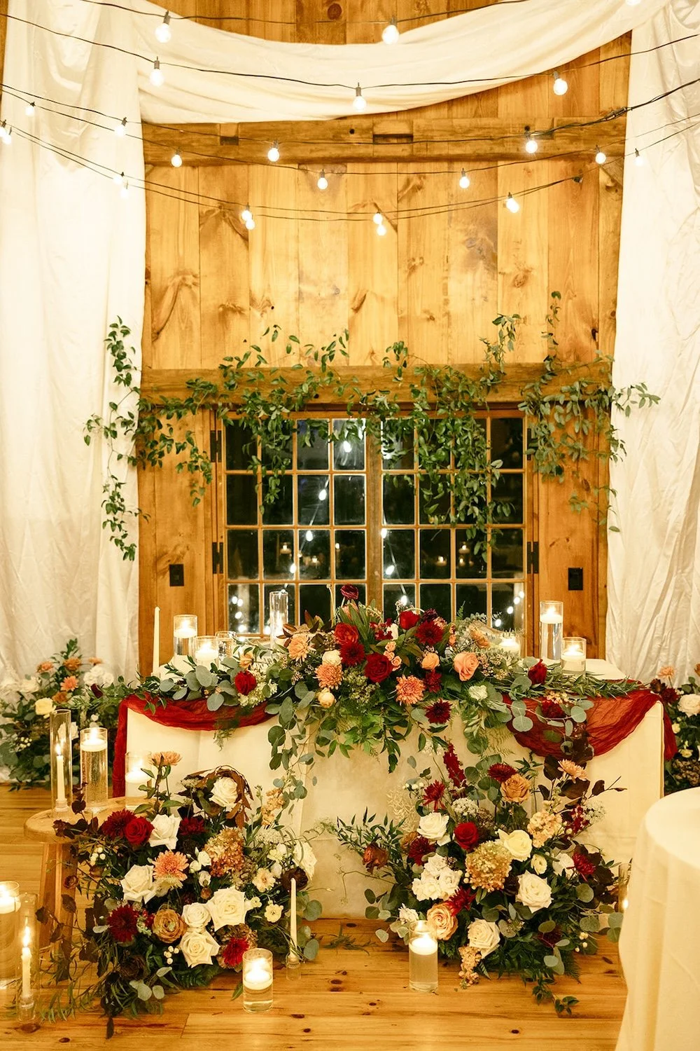 The sweetheart table is decorated with beautiful florals colors of maroon, pinks and ivory.