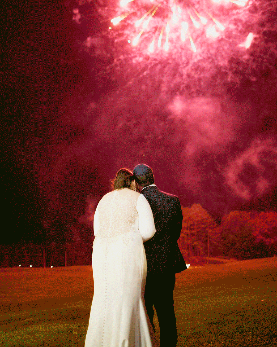 Live photo of the bride and groom admiring the fireworks after their wedding. 