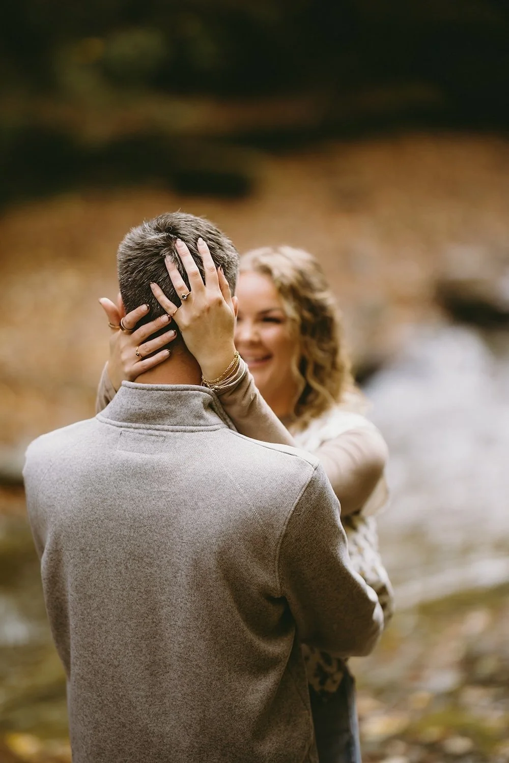 The future bride hold her grooms head showing off her beautiful emerald engagement ring