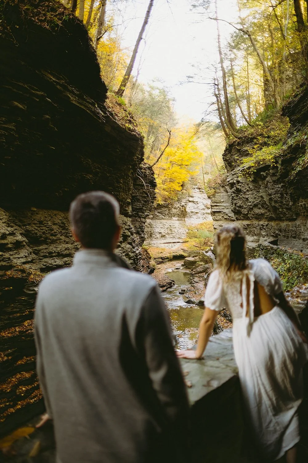 The future bride admires the falls as her groom admires her from a far. 