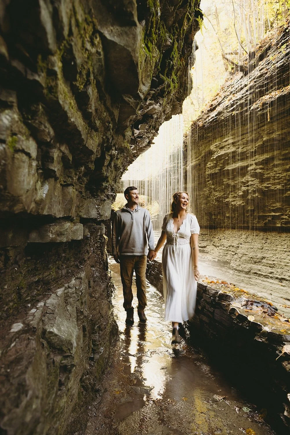 The couple hold hands as the walk underneath one of the waterfalls of the gorge. 