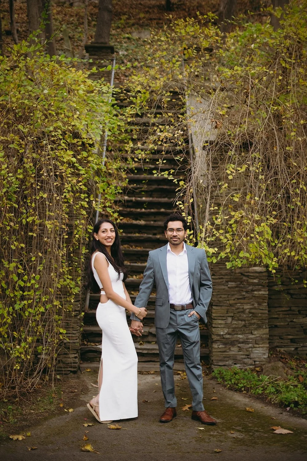 The future bride poses holding her grooms hand at the bottom of the steps. 