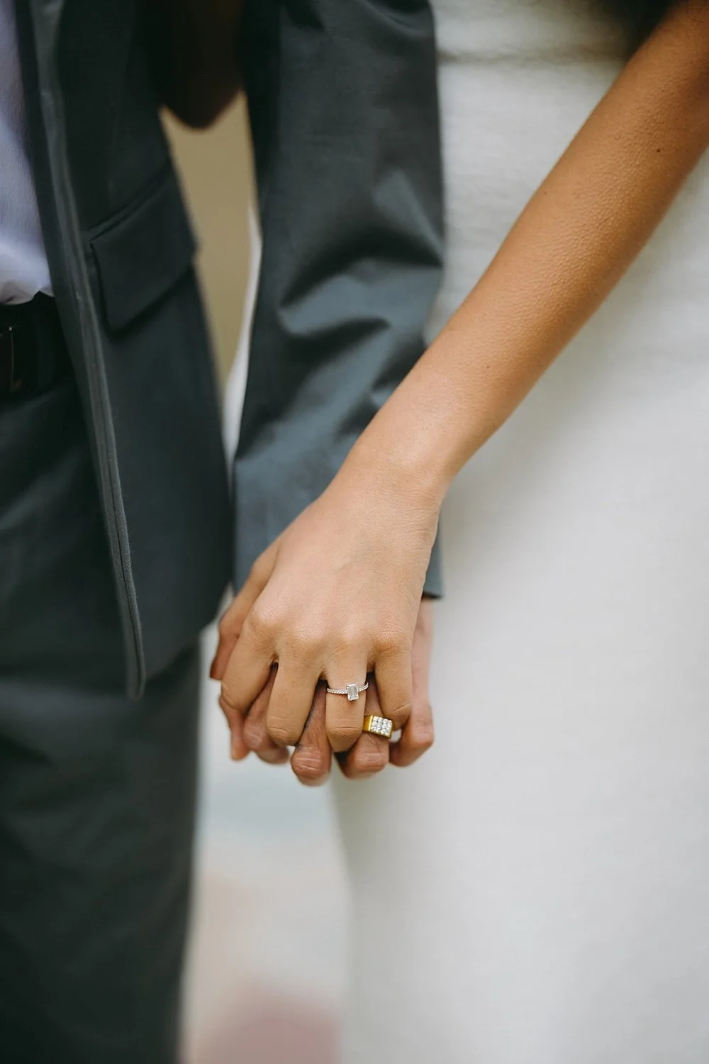 Detail photo of the couple holding hands with their wedding rings on. 