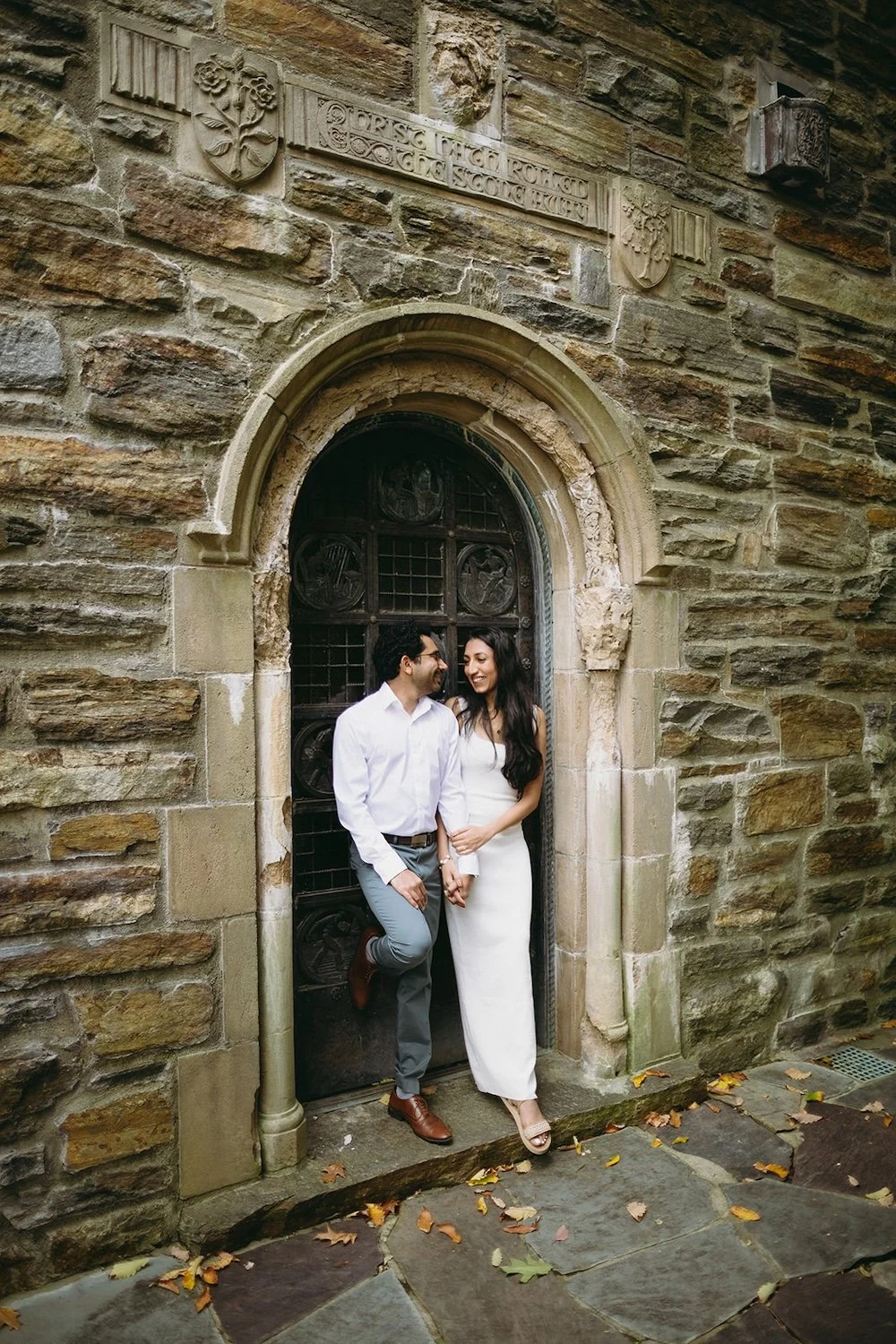 The couple stand in the antique church door way. 