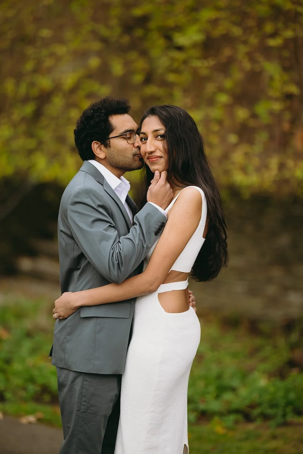 The future groom kisses his bride to be as she looks at the camera. 