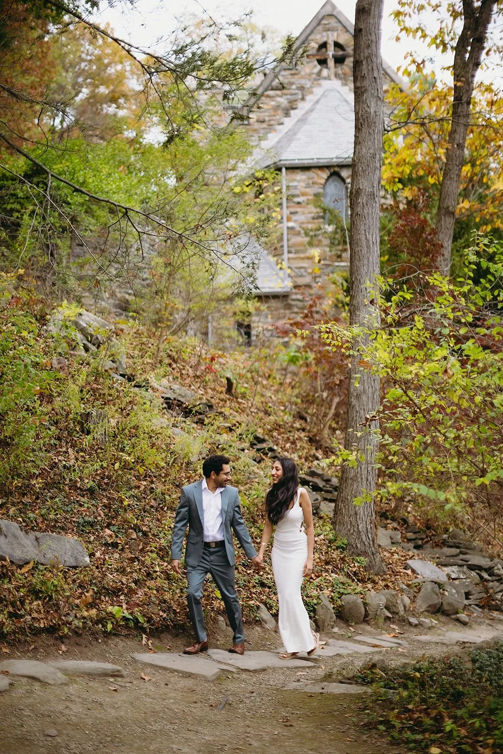 The future groom holds his future brides hand as they walk the exposed brick. 