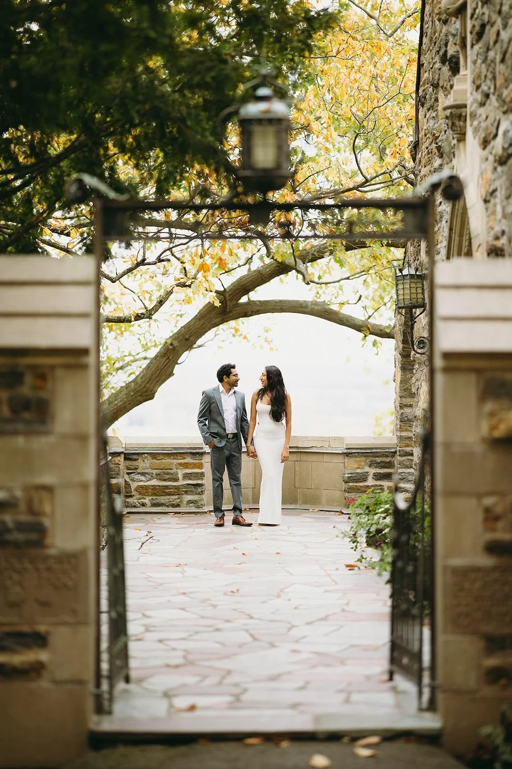 The couple stand on the balcony of the church as the entry way is the frame of their photo. 