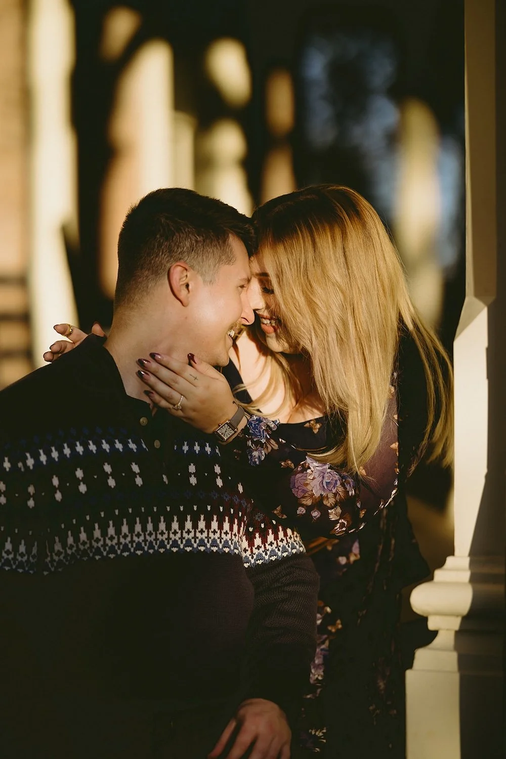 The future bride holds her grooms face close to hers as they share a smile. 