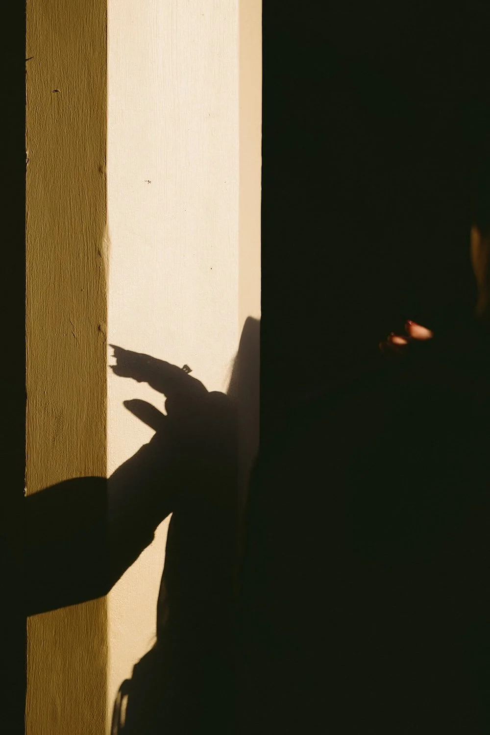 Detail photo of the shadow of the couples hands against the white post. 