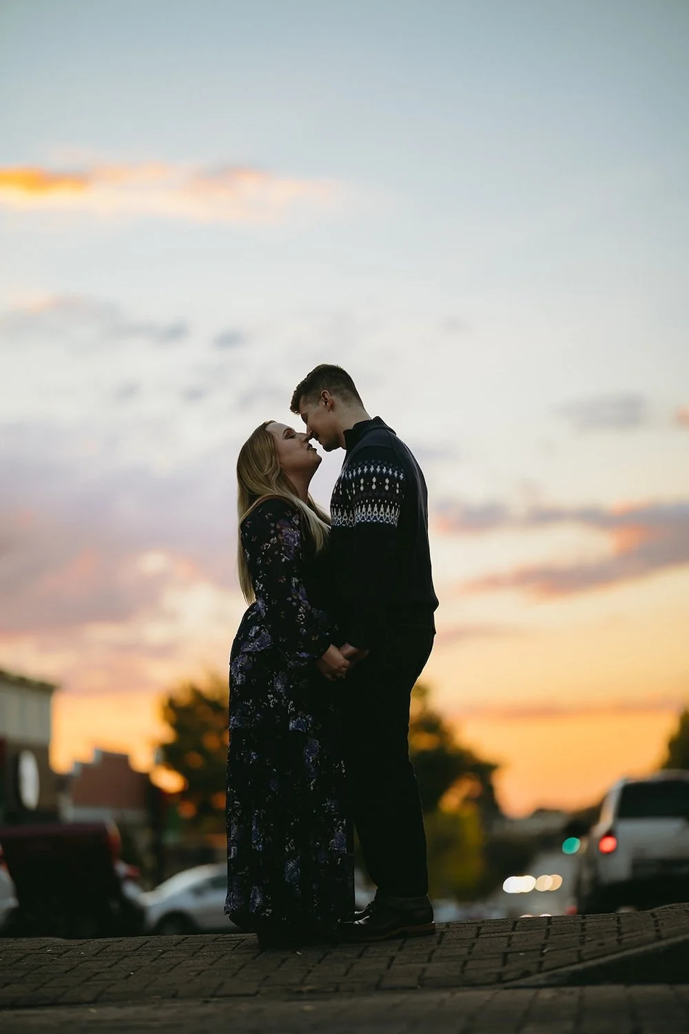 Blue hour photo of the couple standing in the crosswalk looking at one another with the sunset behind them. 