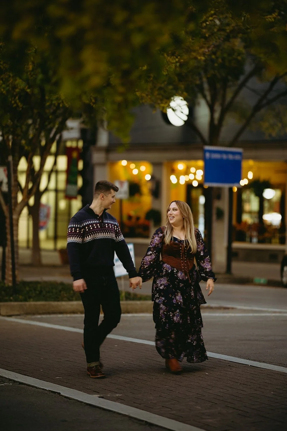 The couple stand hand in hand walking the crosswalk.