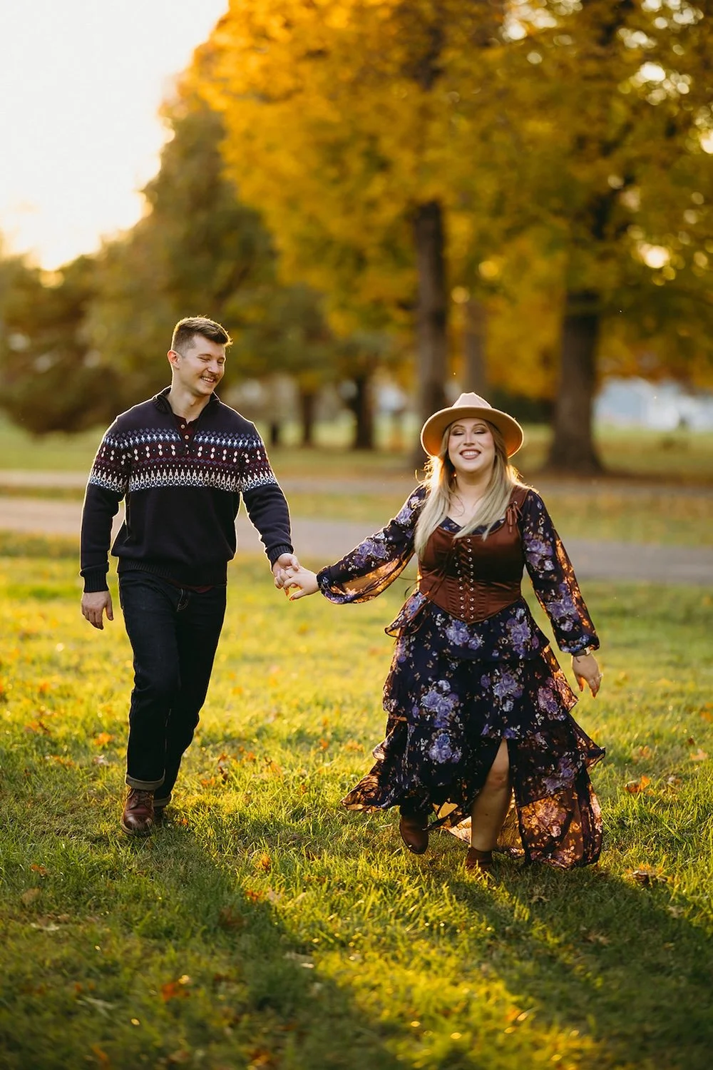 The couple run through the park hand-in-hand. 