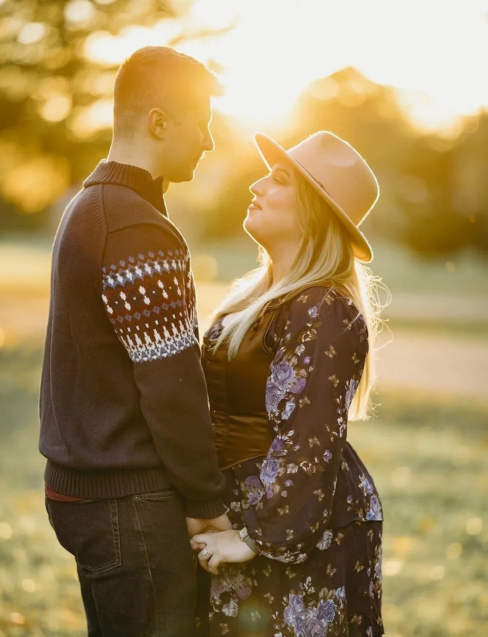 The couple stare into one another eyes with the sun beaming between them. 