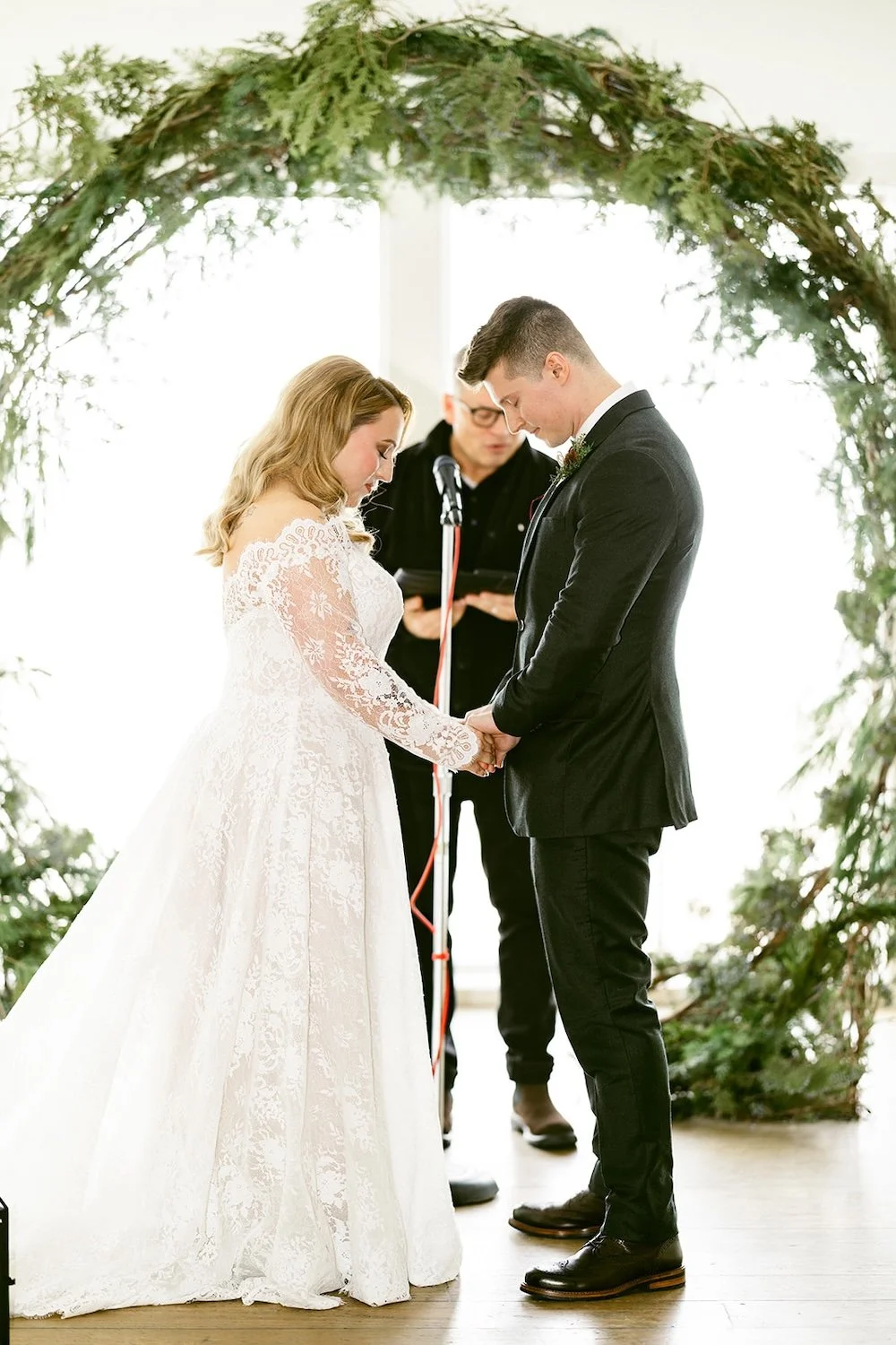 The couple stand in prayer at the arbor. 