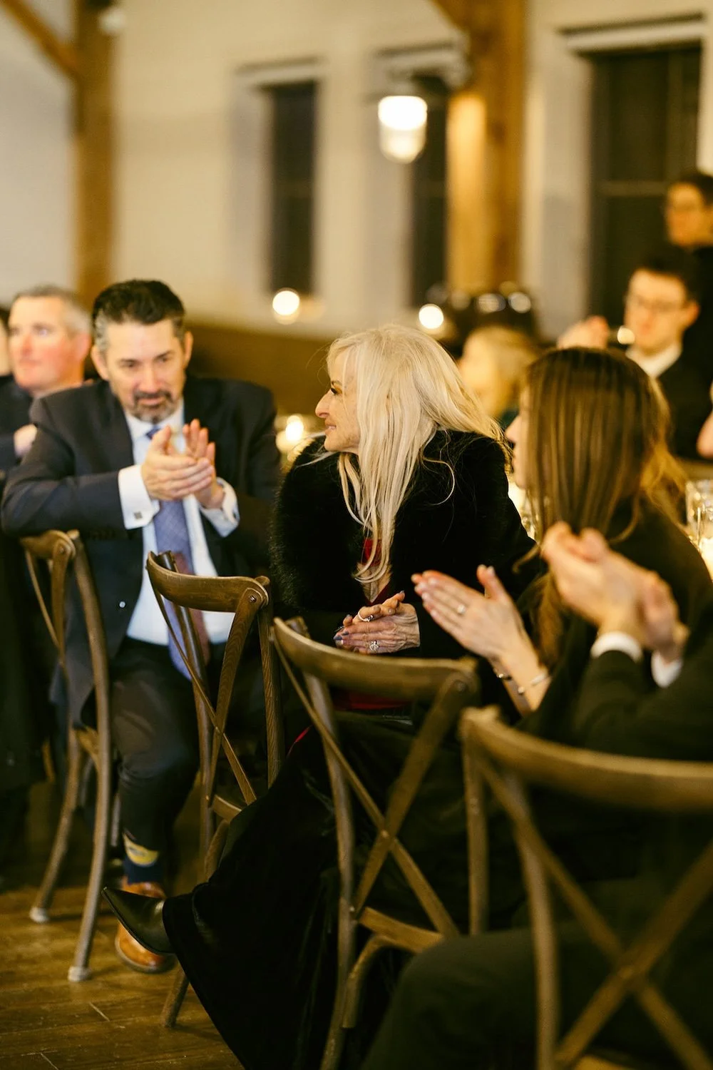 Guests of the couple sitting at the family style table clapping in celebration.