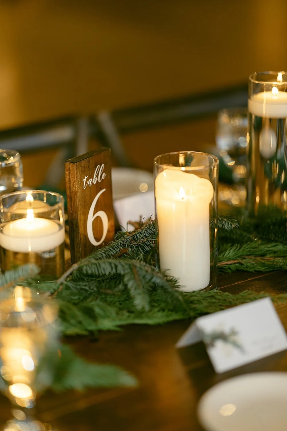 Table number decorated with candles and evergreen branches.