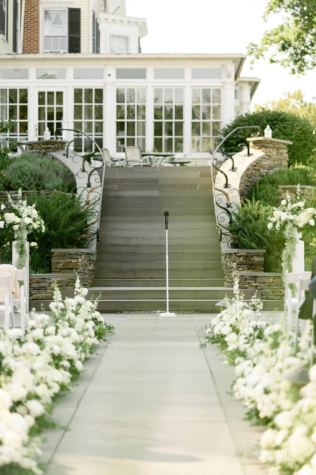 An outdoor wedding ceremony is taking place in front of a large white tent, with guests seated and a couple standing at the altar for an Inn at Taughannock Falls Wedding