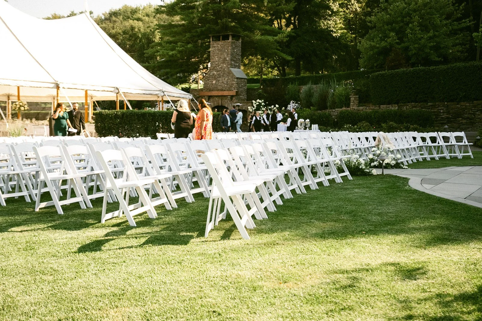 An outdoor wedding ceremony is taking place in front of a large white tent, with guests seated and a couple standing at the altar for an Inn at Taughannock Falls Wedding