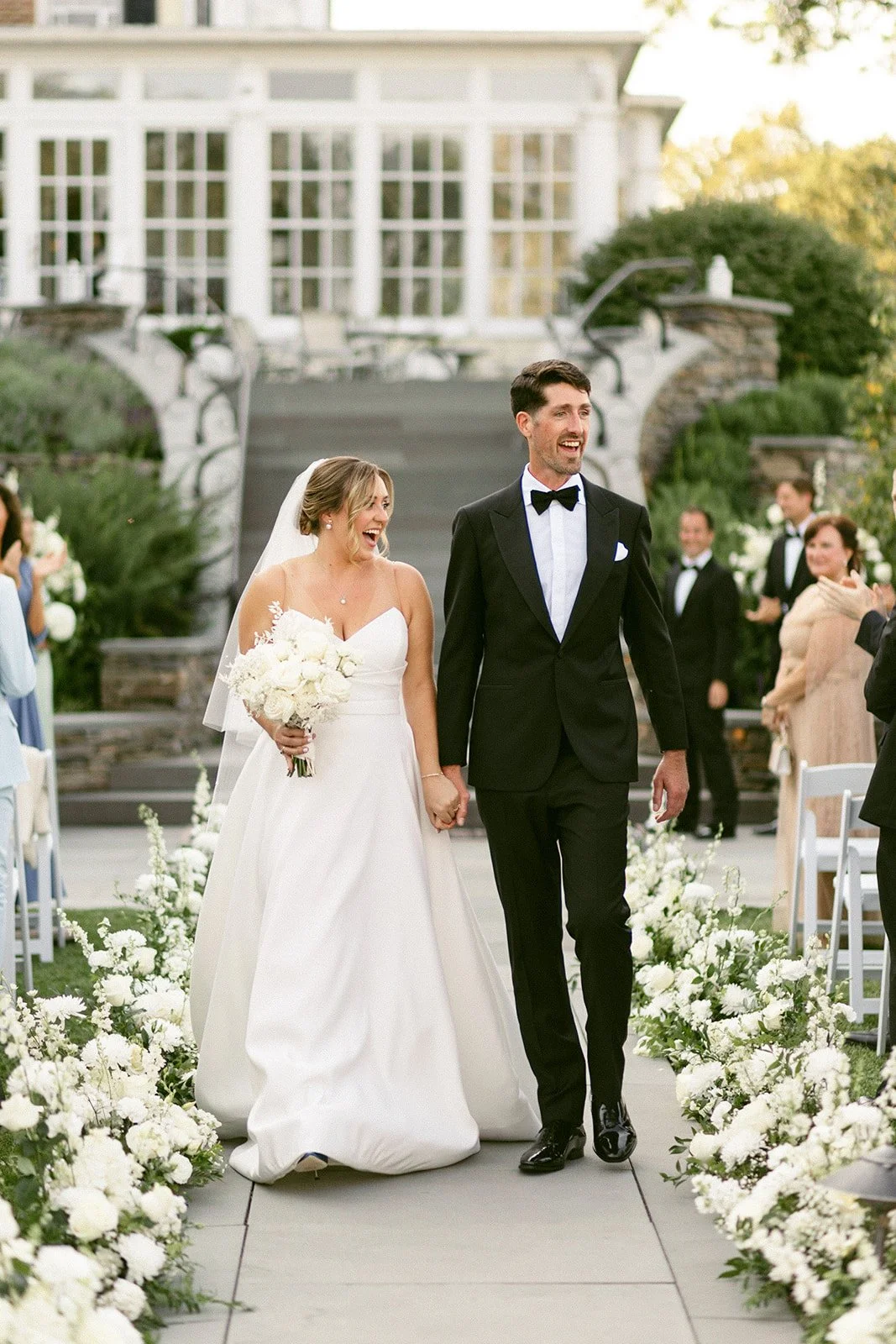 An outdoor wedding ceremony is taking place in front of a large white tent, with guests seated and a couple standing at the altar for an Inn at Taughannock Falls Wedding