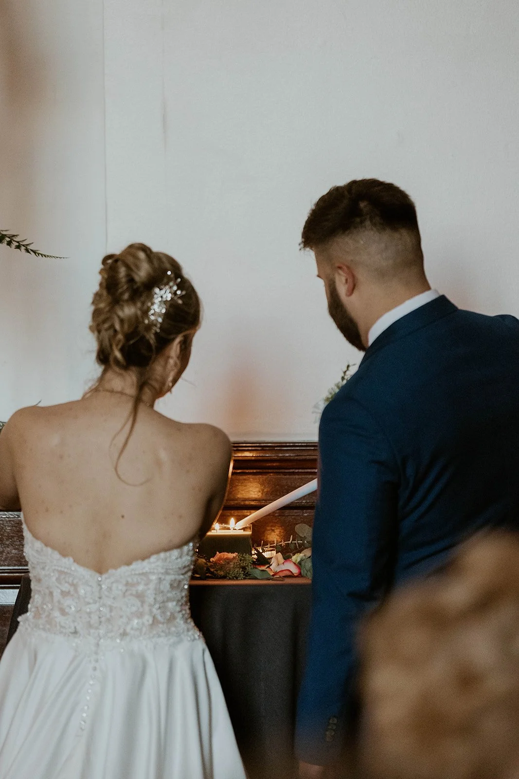 Bride and groom lighting a unity candle during their wedding ceremony, a meaningful Christian wedding ceremony idea.