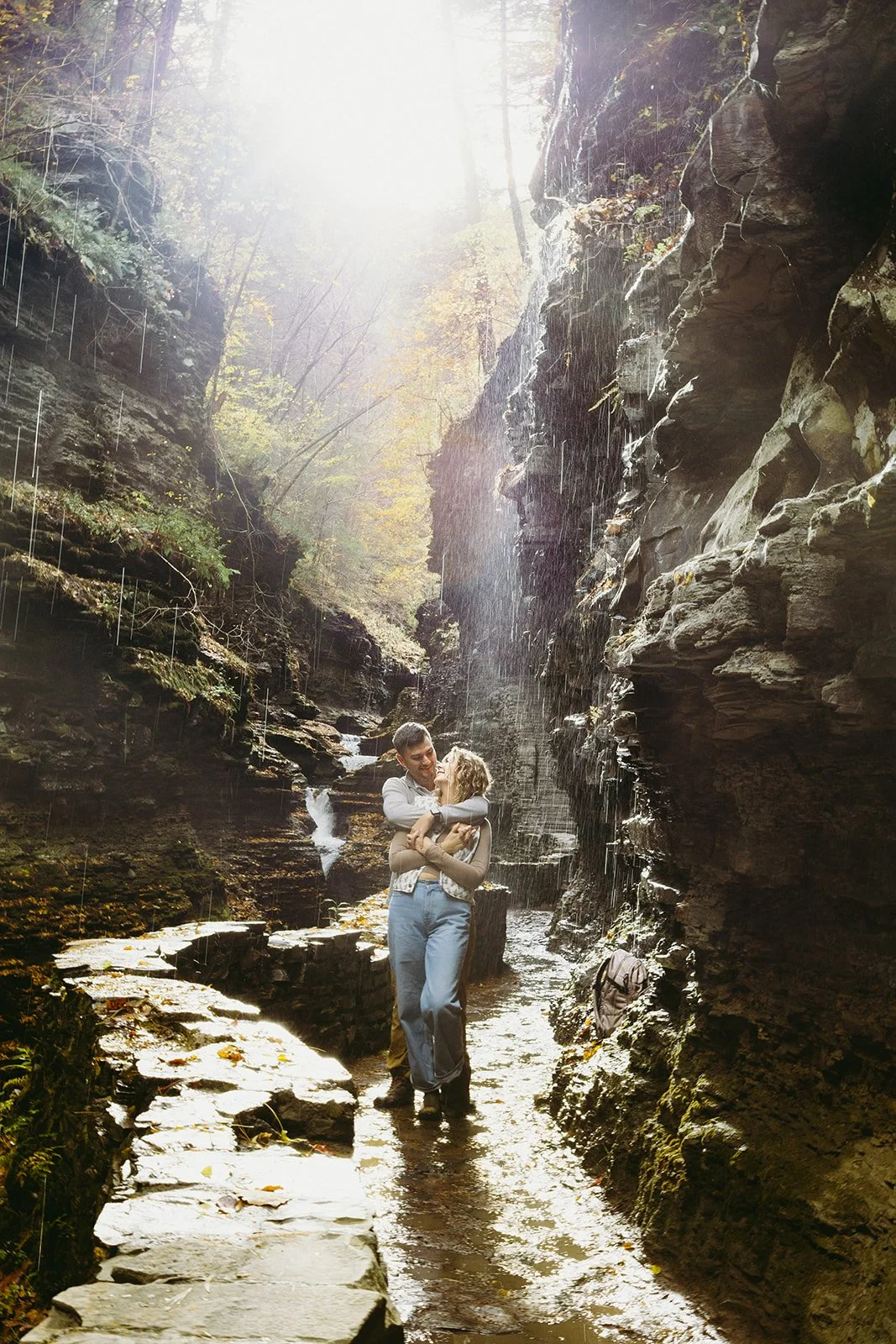 Couple standing beneath a waterfall at Watkins Glen, one of the most scenic waterfalls in Upstate NY