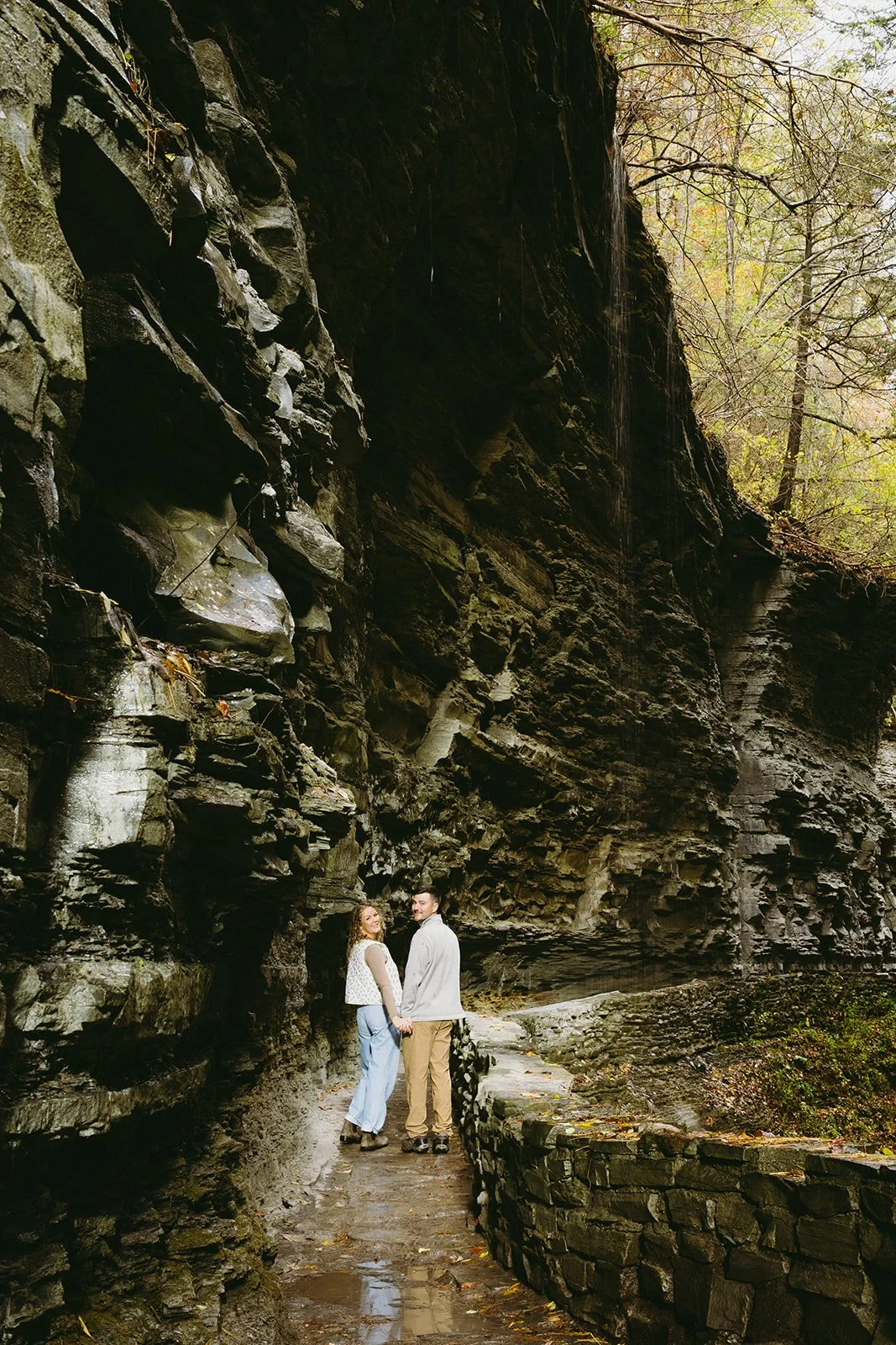 Couple standing beneath a waterfall at Watkins Glen, one of the most scenic waterfalls in Upstate NY