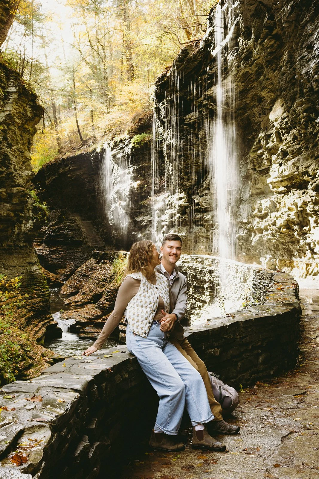 Couple standing beneath a waterfall at Watkins Glen, one of the most scenic waterfalls in Upstate NY