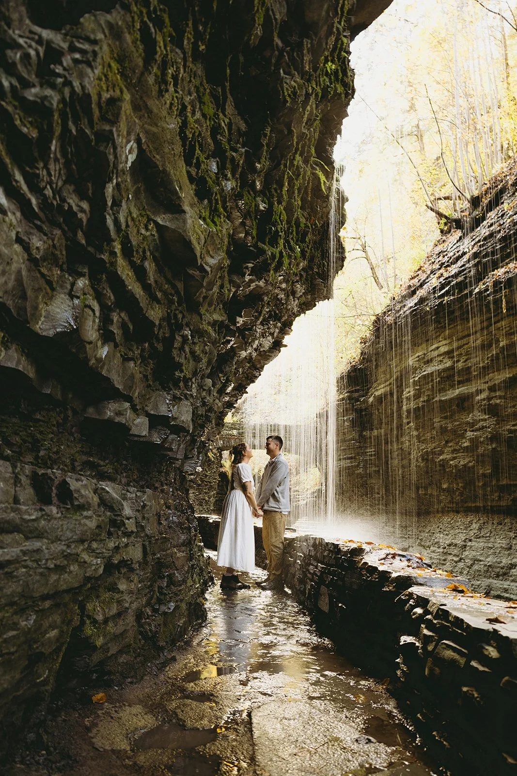 Couple standing beneath a waterfall at Watkins Glen, one of the most scenic waterfalls in Upstate NY