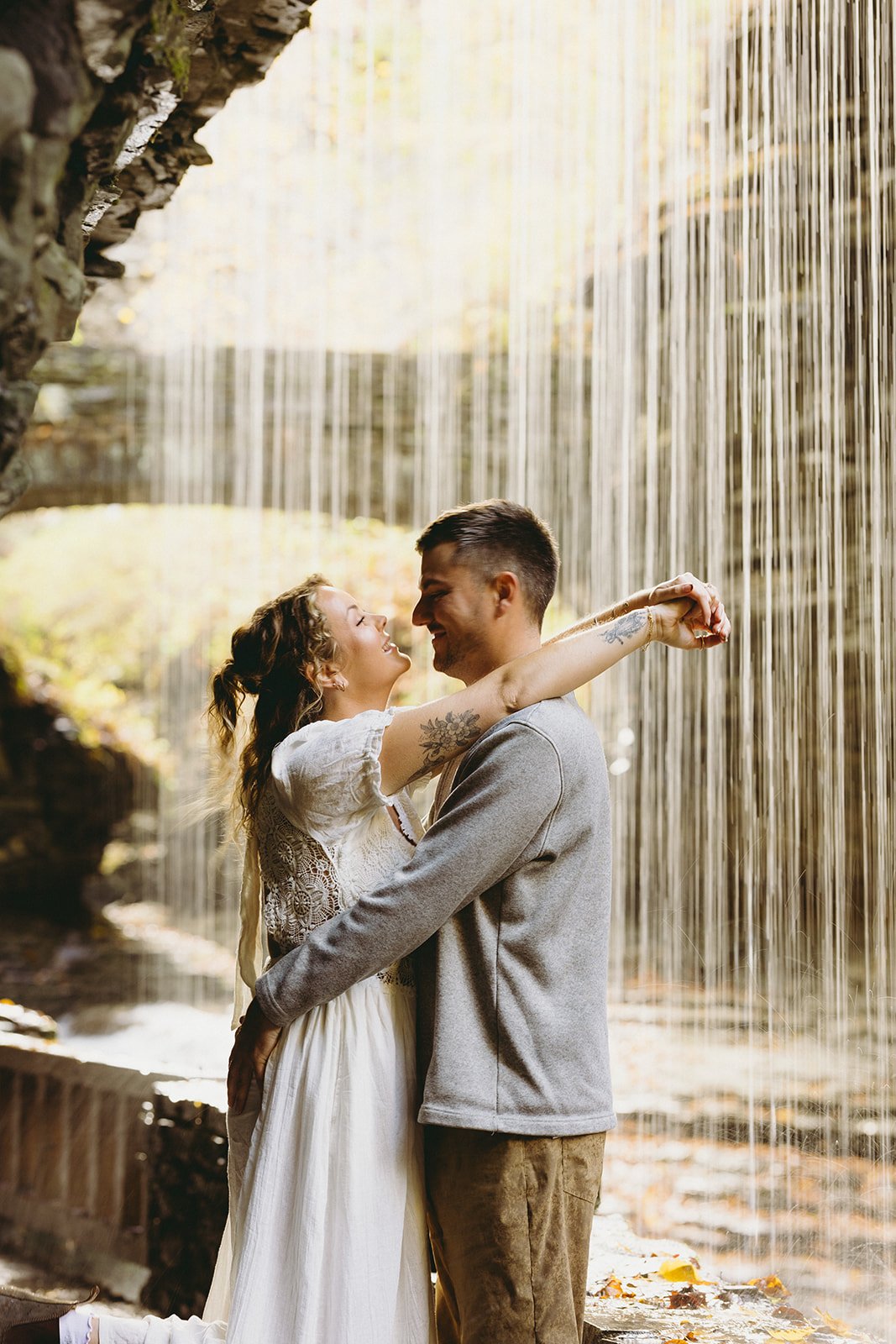 Couple standing beneath a waterfall at Watkins Glen, one of the most scenic waterfalls in Upstate NY