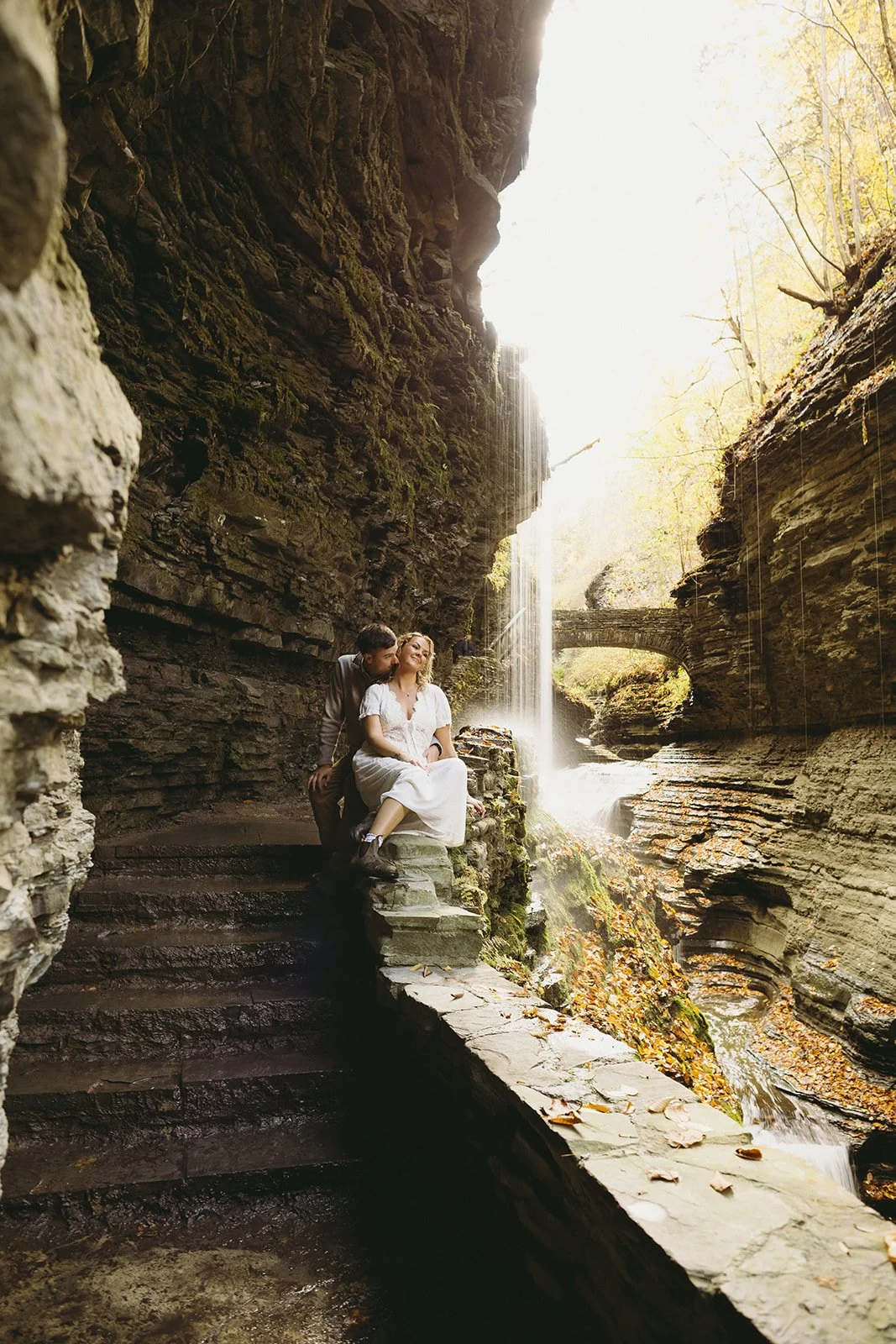 Couple standing beneath a waterfall at Watkins Glen, one of the most scenic waterfalls in Upstate NY