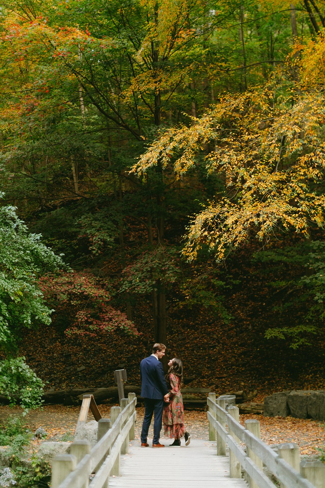 A couple walking hand-in-hand down a path lined with autumn trees.