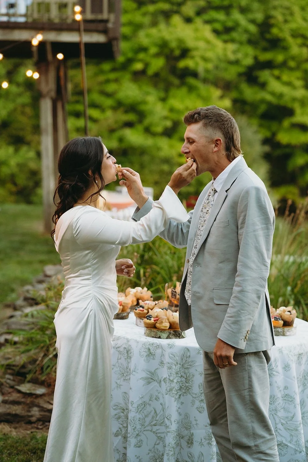 The bride and groom share their first bites of desert together while feeding one another.