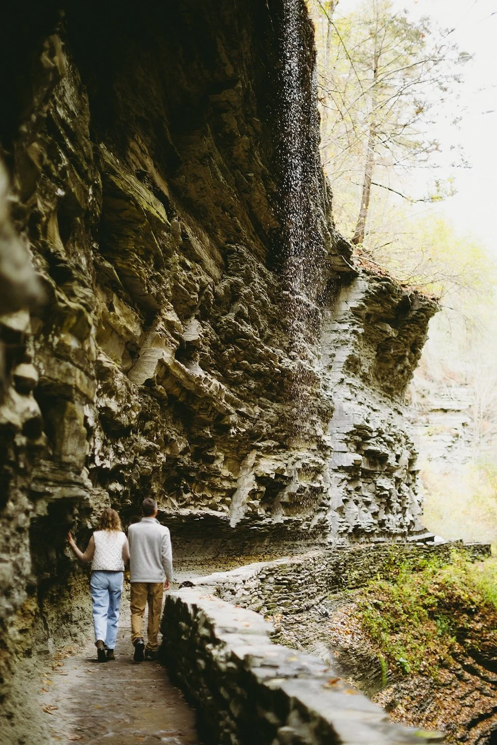 The future bride runs her hand against the rock as the walk the gorge together.