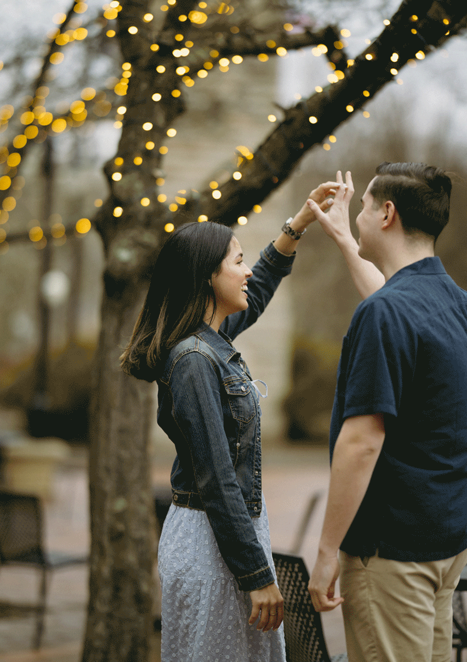 Male spins his fiance in circles as she smiles and laughs with him.